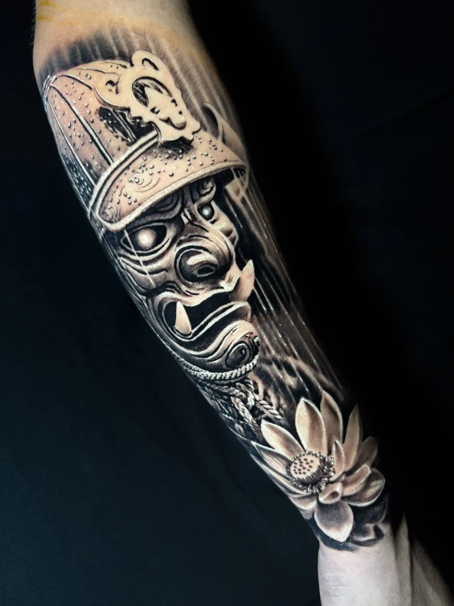 Máscara de samurai com flor de lótus em realismo no antebraço